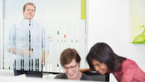 A man in an office eavesdrops on two female colleagues.