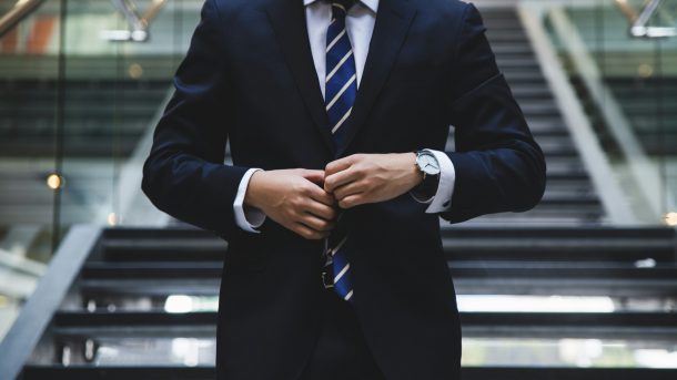 Banker wearing a dark suit adjusting his tie.