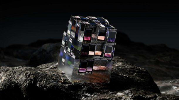 An abstract, metallic cube with digital screens sits on a dark, rocky landscape.